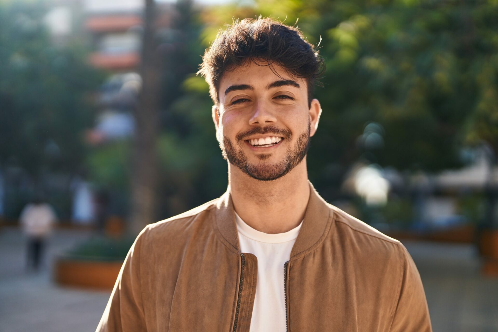 Un jeune homme souriant en plein air, transmettant une image de positivité et de confiance.